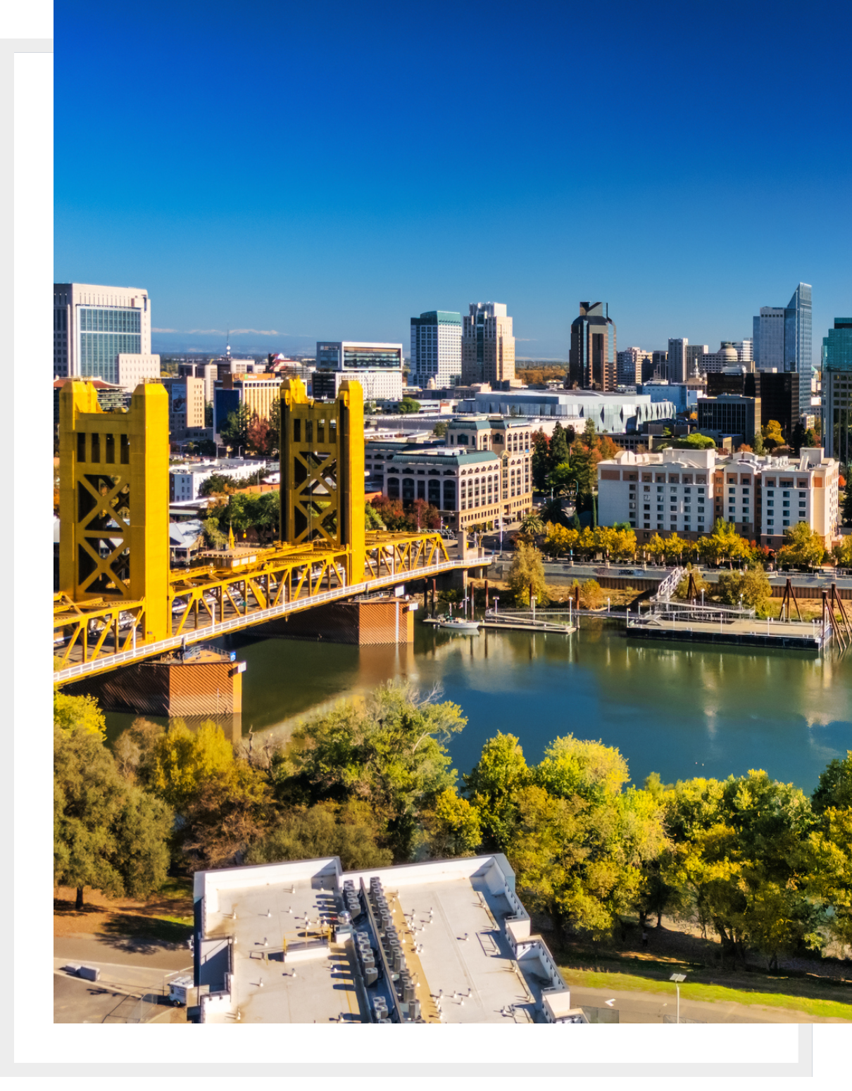 A vibrant cityscape with a yellow bridge over a river and lush greenery.
